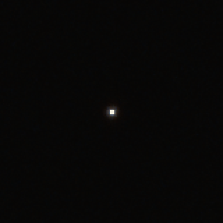 Two enlarged crops of a bright white point on a dark background. Left, with rem-jet: a faint thin red rim. Right, without rem-jet: a wider, stronger red-orange halo.: With rem-jet (5219)